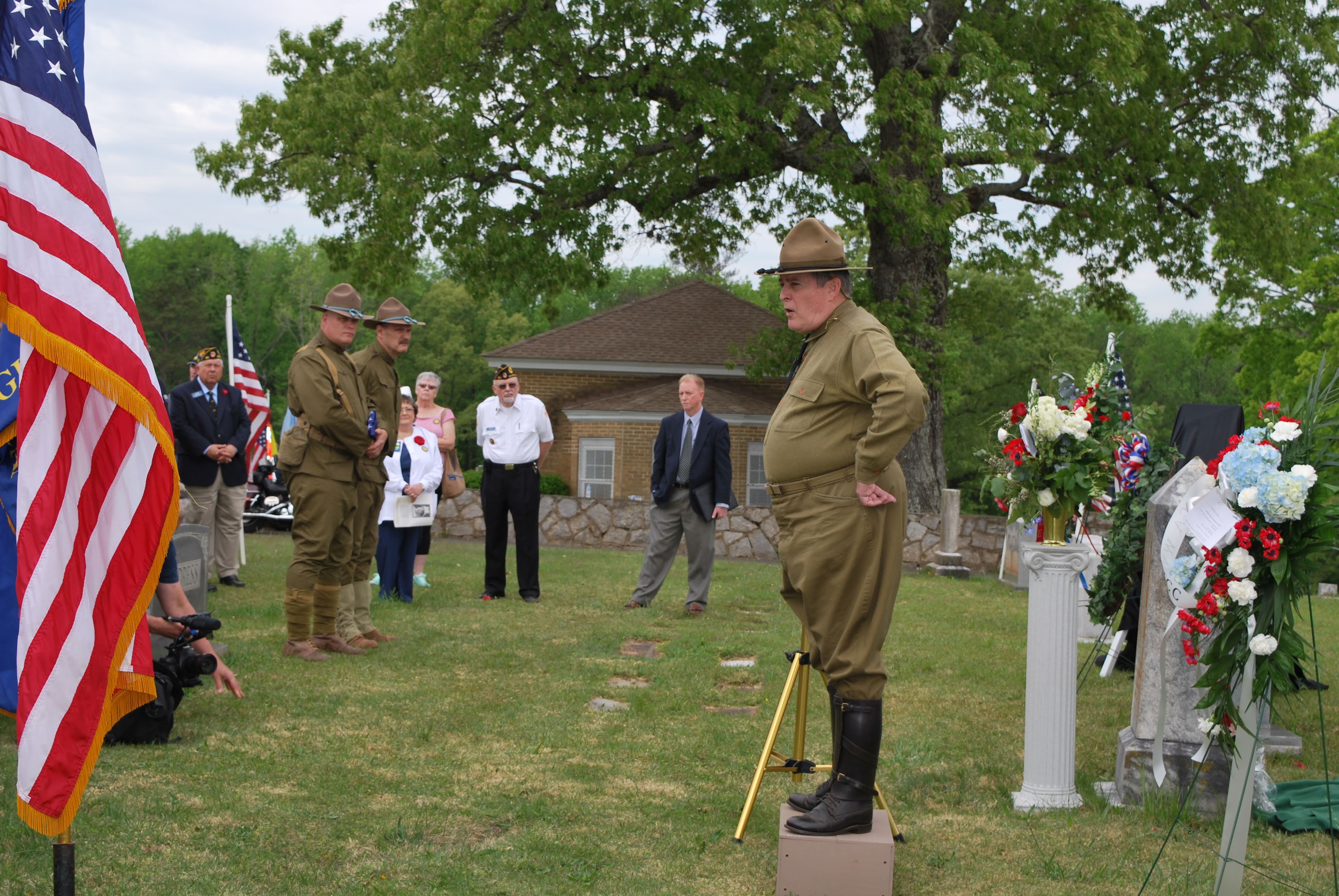 Soldier dressed in WW1 military attire stands atop a box and gives a speech