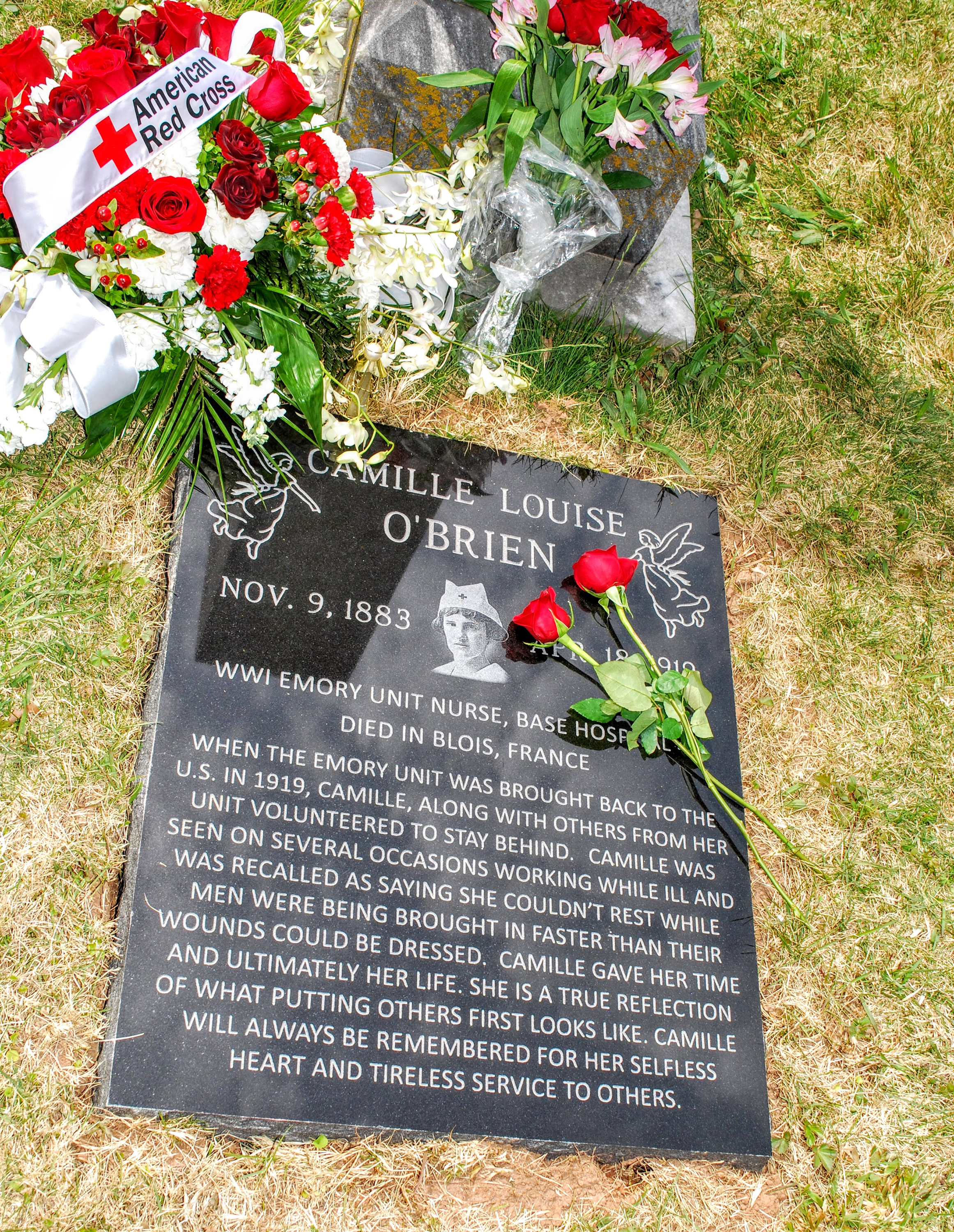 Grave marker for Camille O'Brien. Two red roses lying on top