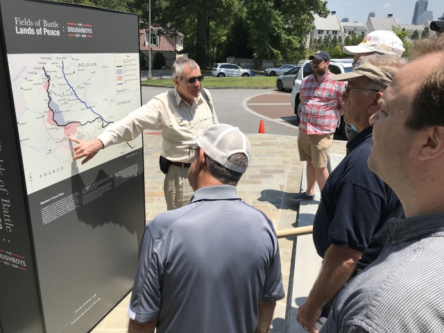 Man talks to a crowd while pointing at a map