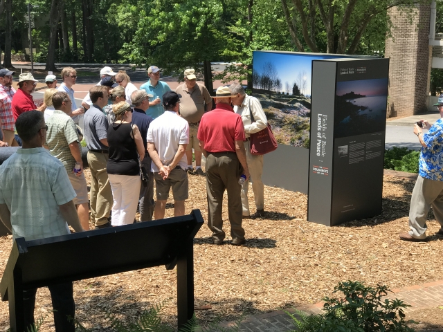 Man speaking to a crowd while standing in front of an outdoor display