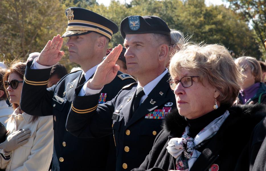 Two soldiers in uniform stand at attention and salute