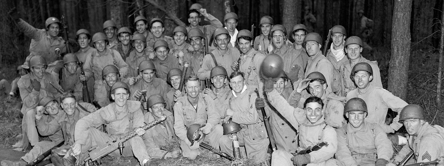 Group of about 50 soldiers sitting on the ground taking a celebratory fun picture