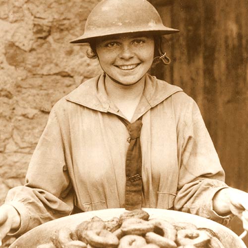 Donut Girl, or Donut Lassie in tin helmet holding a pan of confections